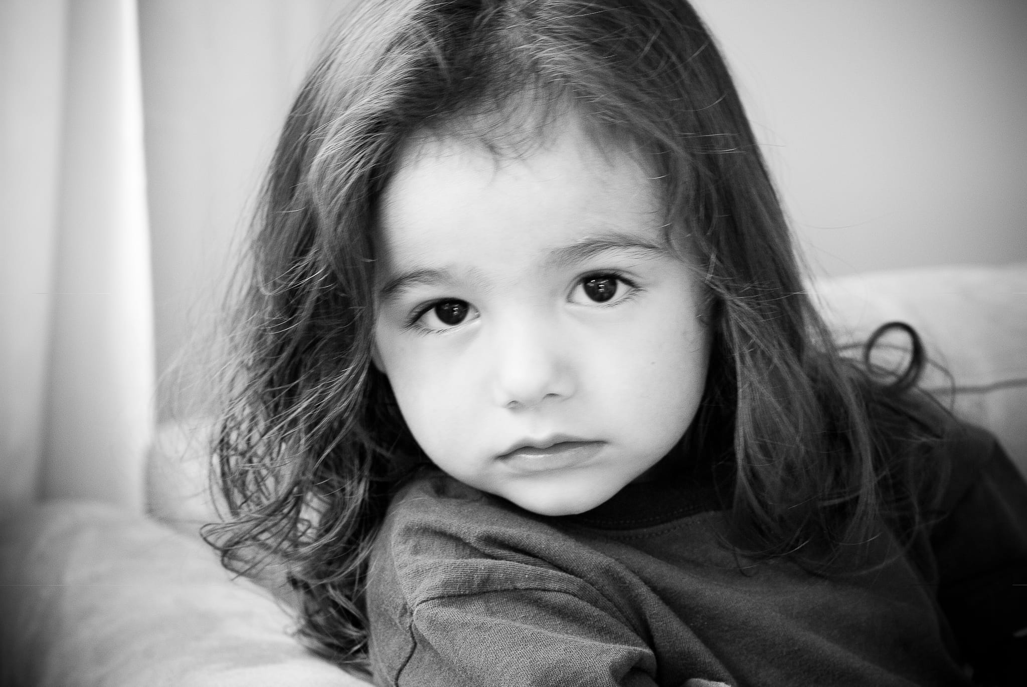 Young boy with long hair before his first haircut, looking directly into the camera with calm, unguarded presence. Black and white portrait by Arnold Szmerling.
