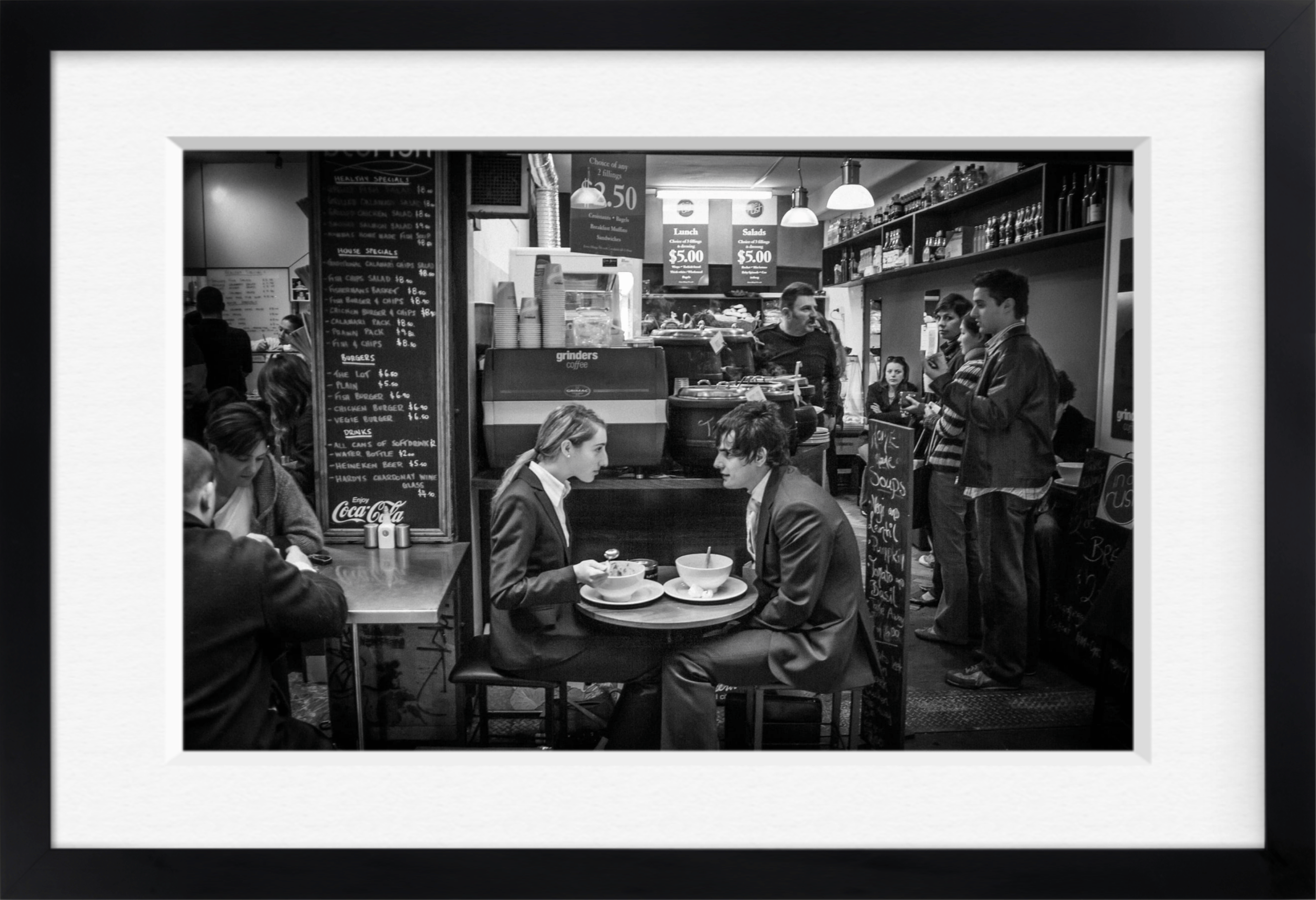 Black and white framed archival print of a busy café with two people seated at a small table