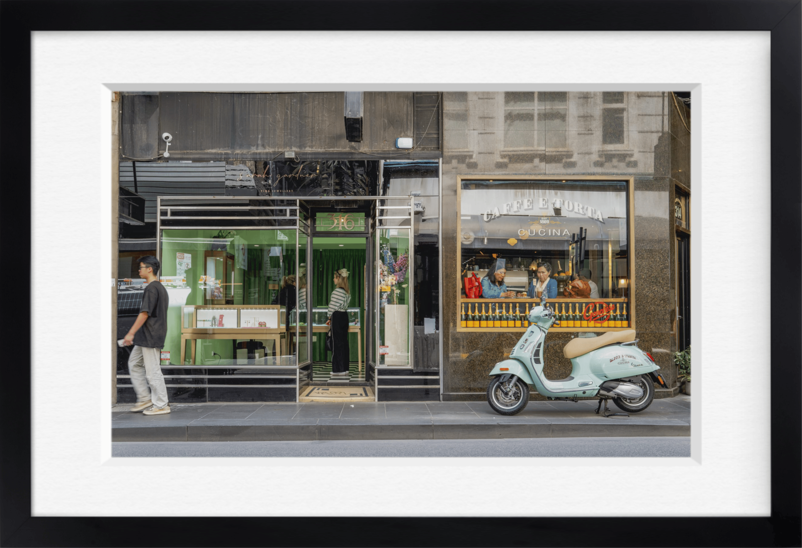 Framed archival print of jewellery and café shopfronts with a light blue scooter parked outside