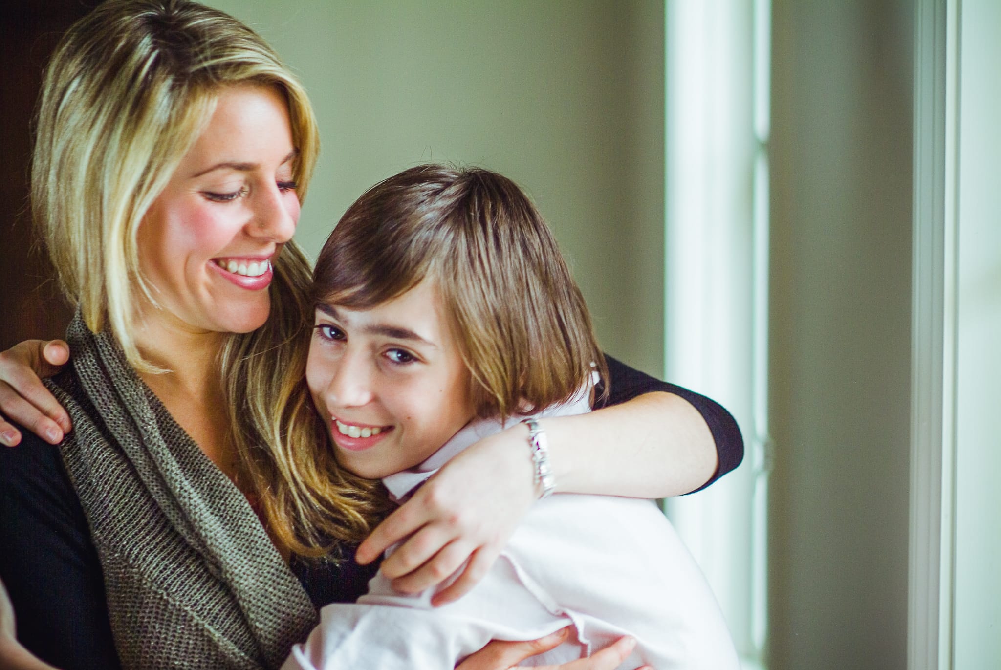 A brother and sister in a tender embrace in warm window light — Arnold Szmerling Visual Legacy Artist