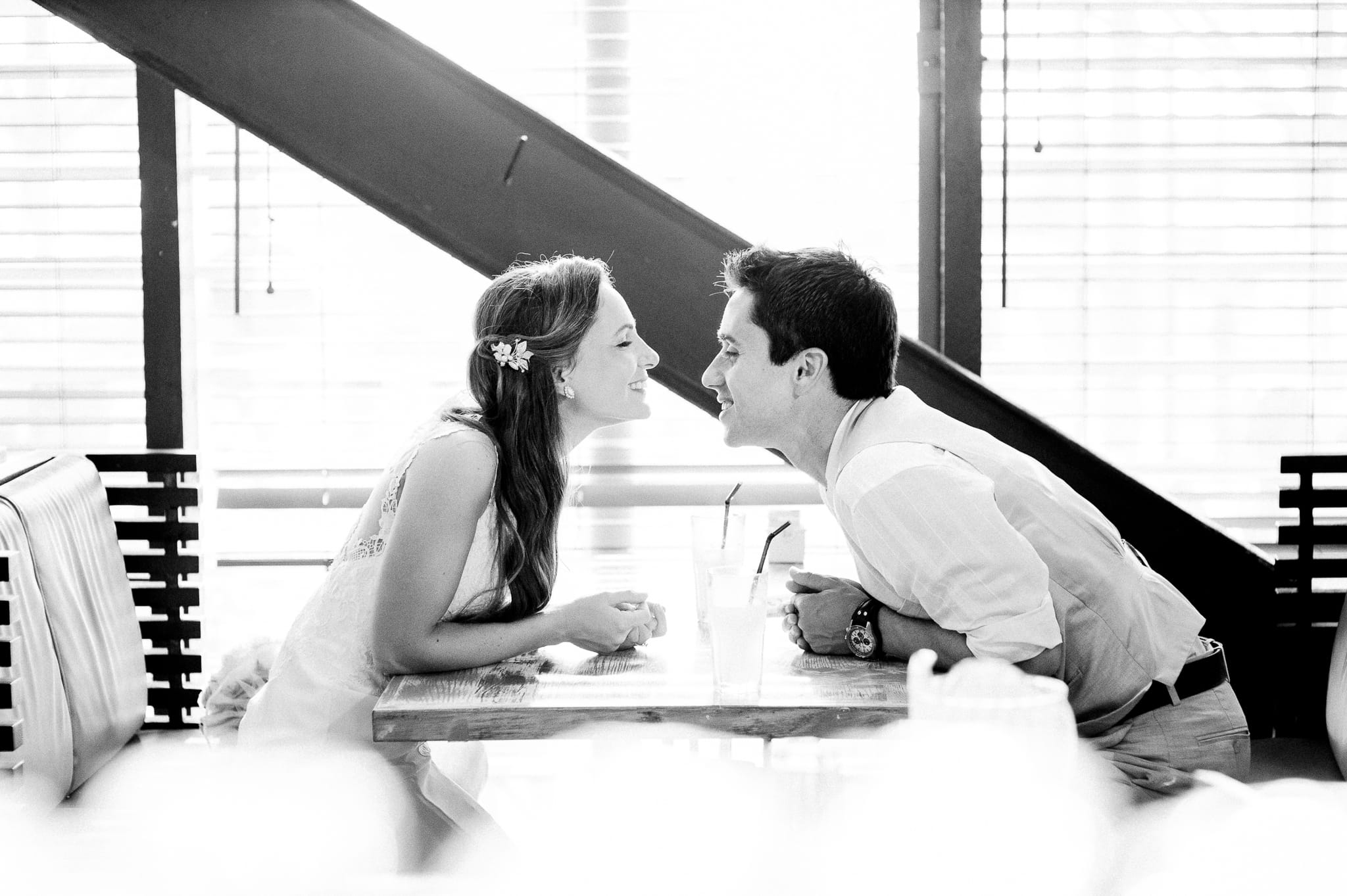 Candid black and white portrait of a couple sharing a joyful moment at a café table — Arnold Szmerling Visual Legacy Artist