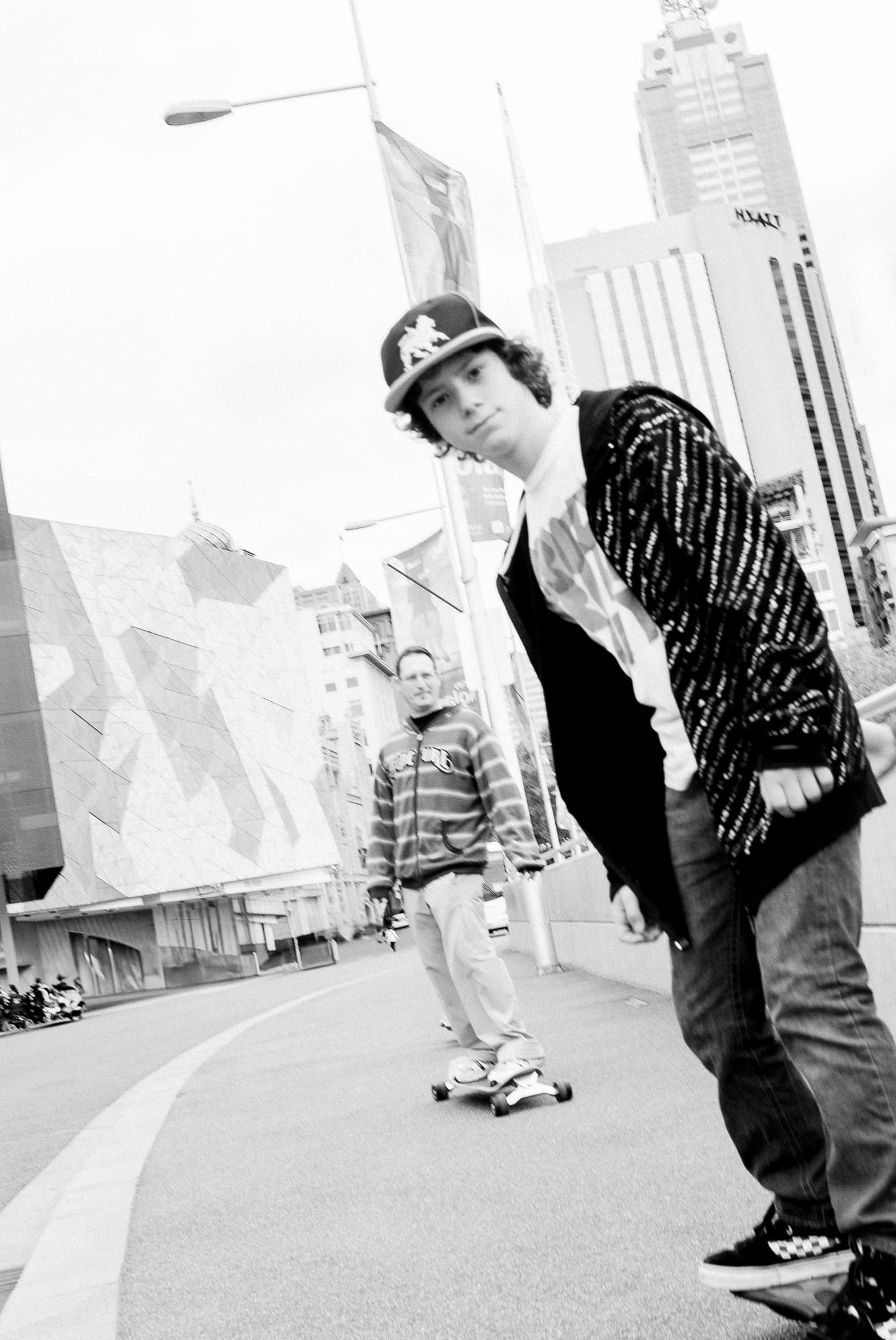 Father and son skating together in Melbourne – joyful, authentic family bond captured in natural light by Arnold Szmerling