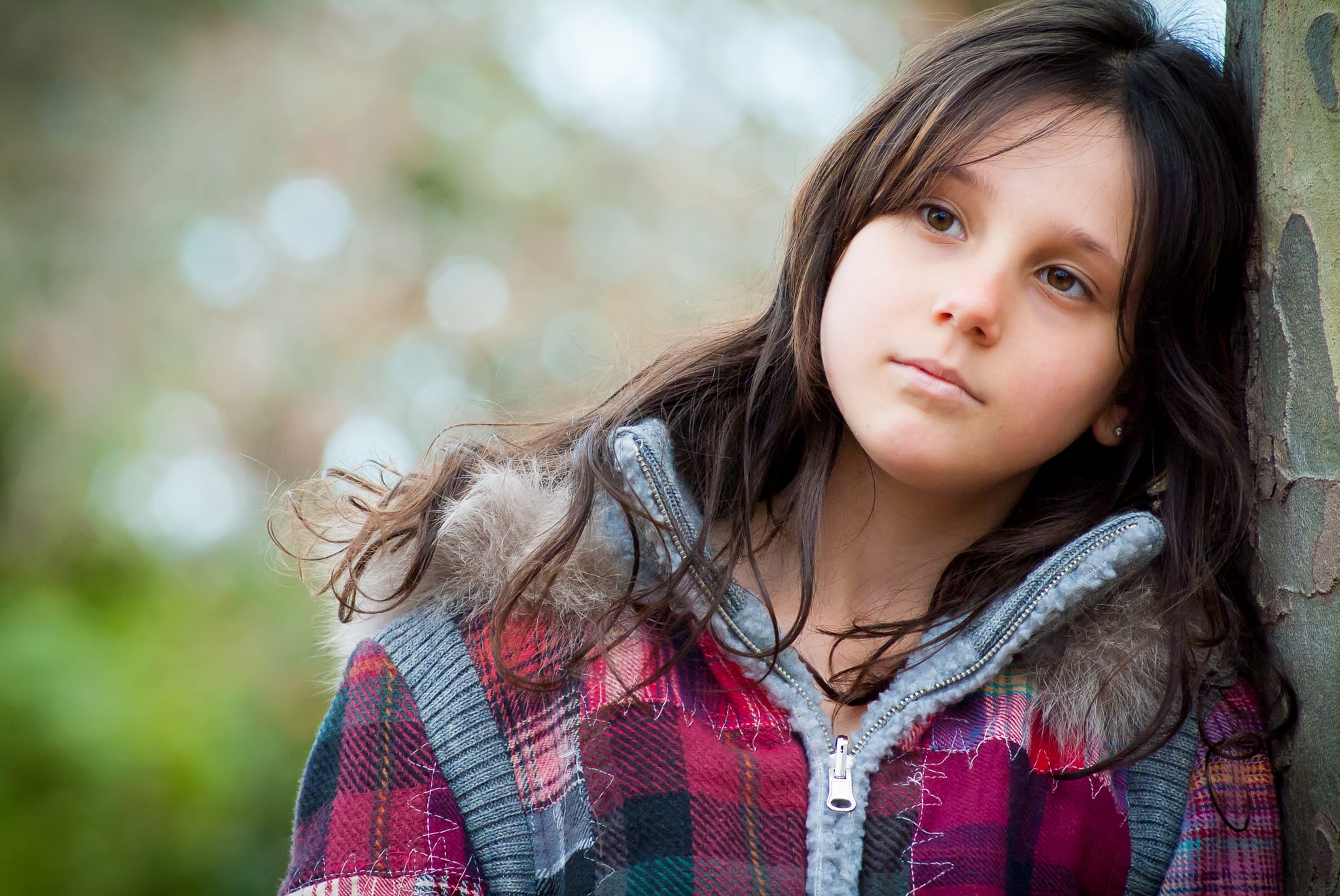 A young girl leaning against a tree with a dreamy upward gaze in a plaid jacket — Arnold Szmerling Visual Legacy Artist