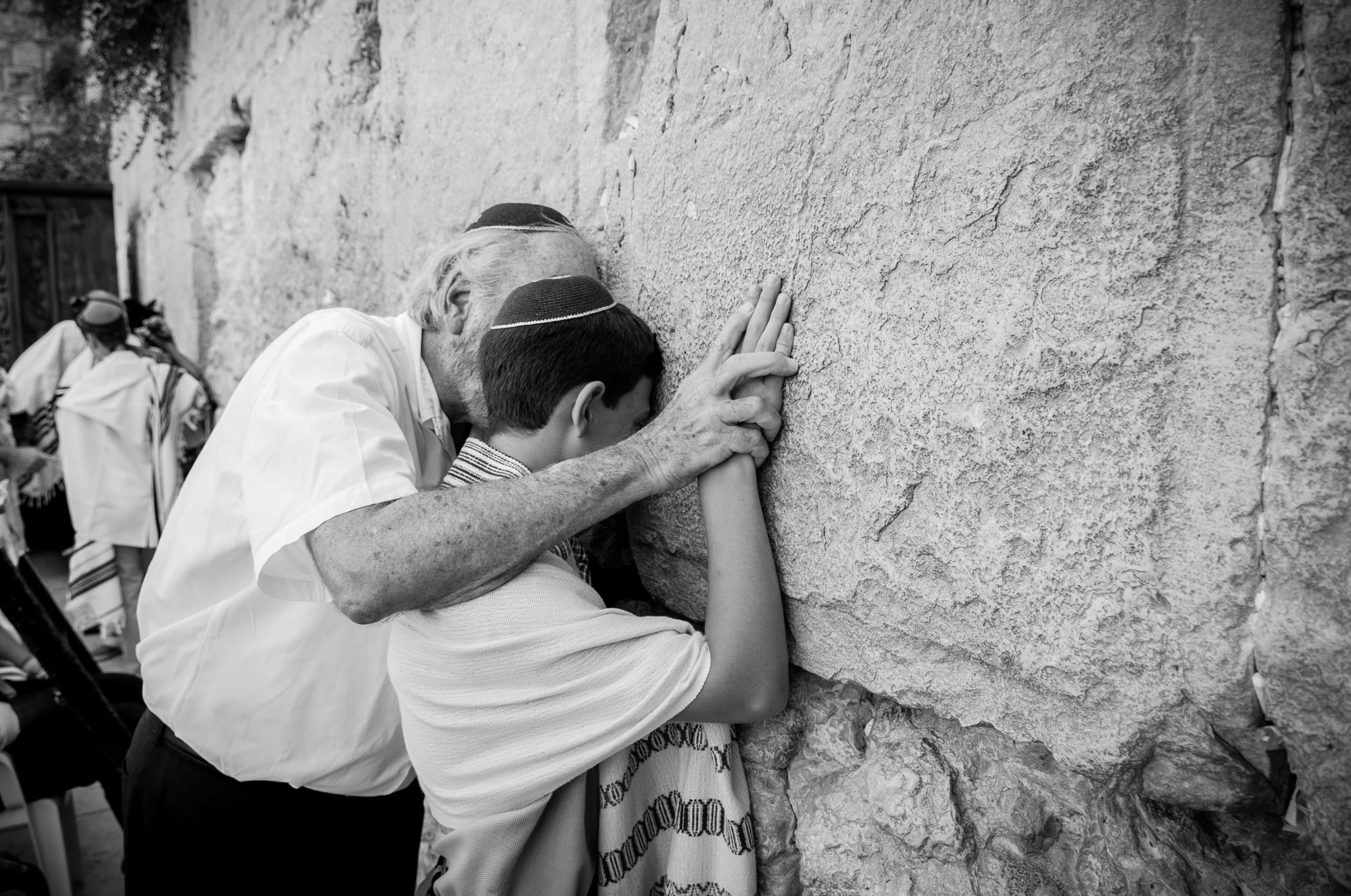 Cinematic black and white portrait of a grandfather and grandson praying together at the Western Wall, Jerusalem — Arnold Szmerling Visual Legacy Artist