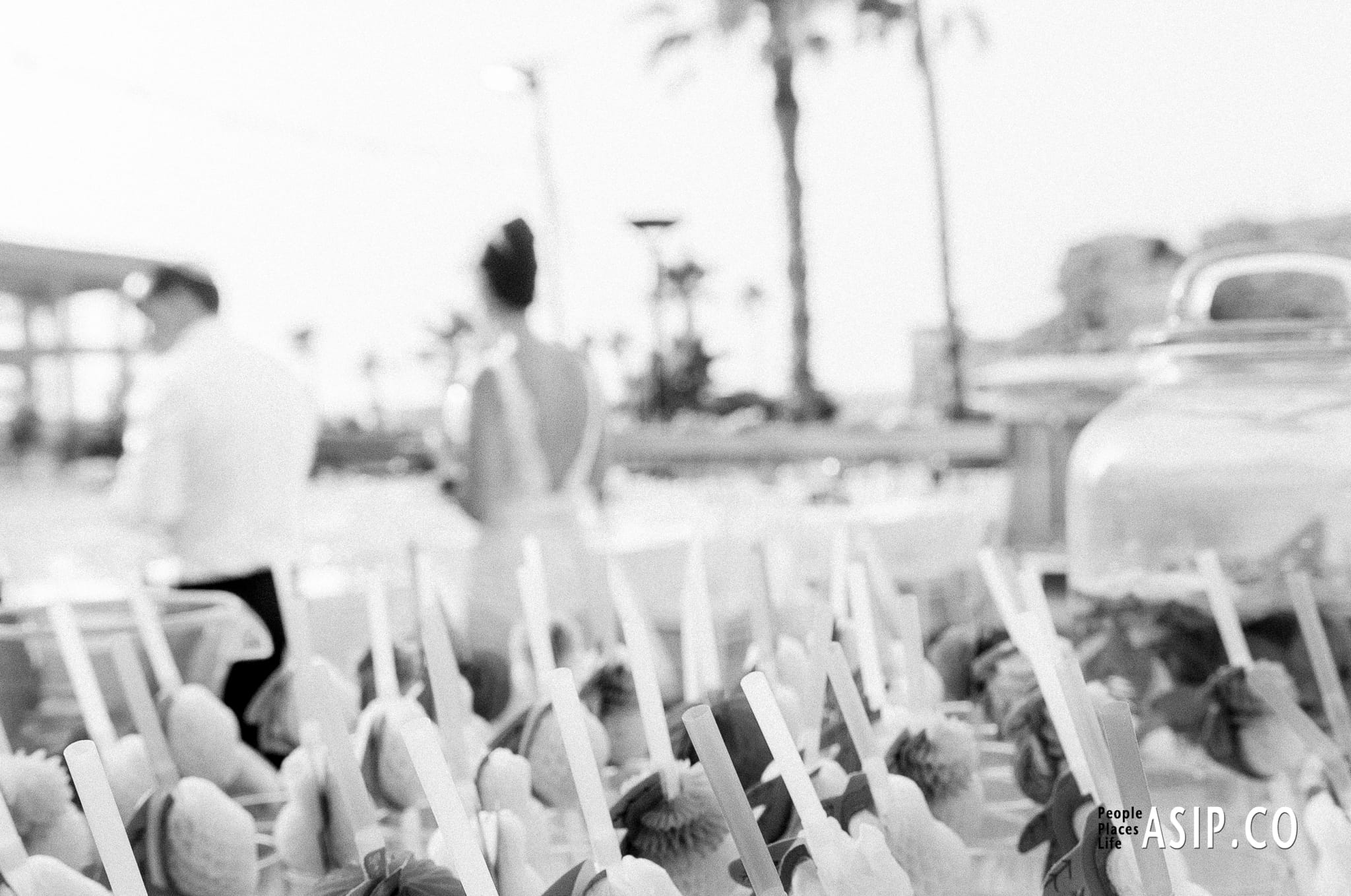 A stylish editorial of bride and groom at of focus in the background with finger food front of camera captured with a cinematic, analog-inspired aesthetic by Arnold Szmerling. This manifestation emphasizes the play of bokeh with grain and visual restraint of the Visual Life Collection.