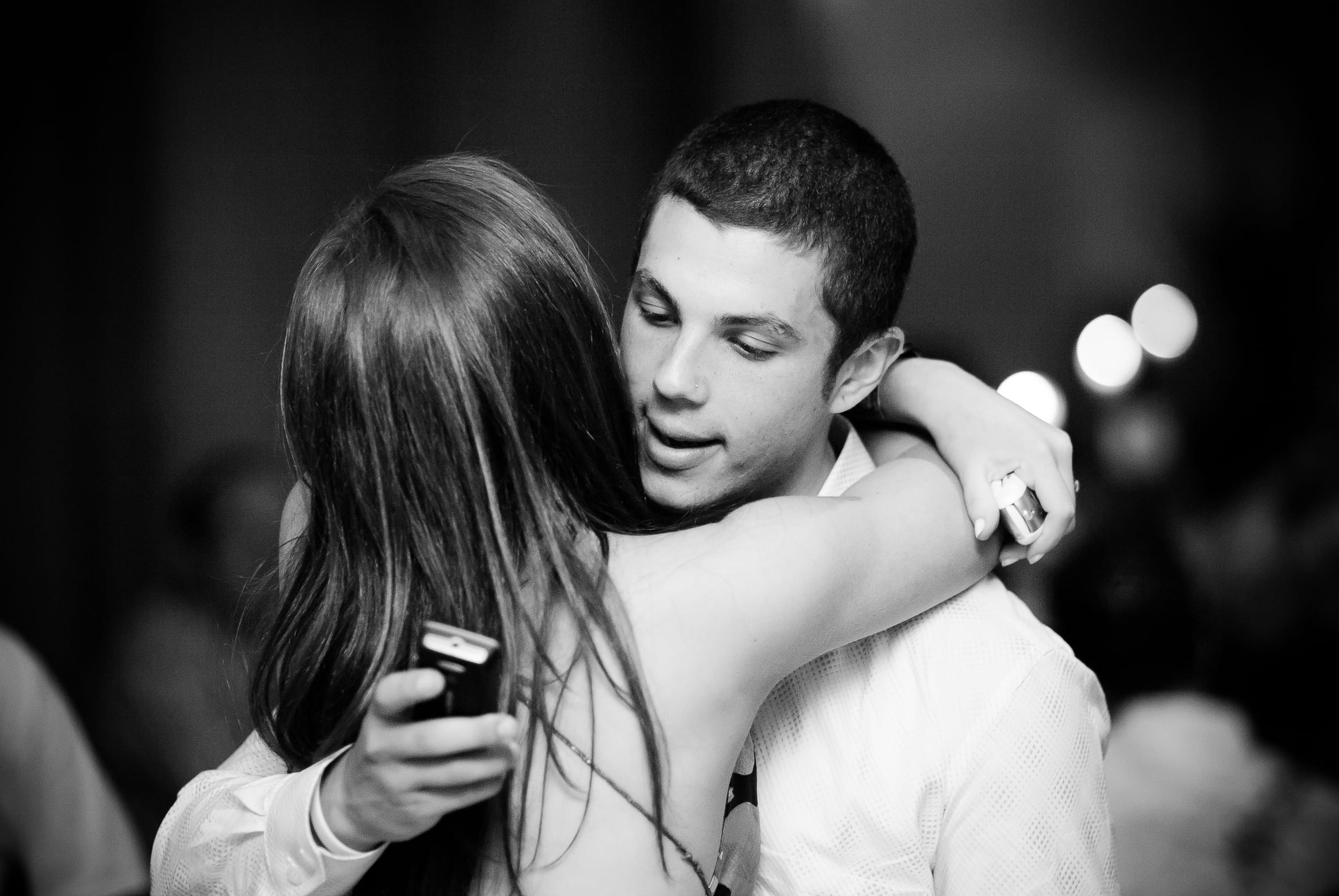An iconic candid in black and while of teen boy checking is phone while dancing with female, Melbourne, Australia, captured with natural light for the 2026 Founder’s Residency by Arnold Szmerling.