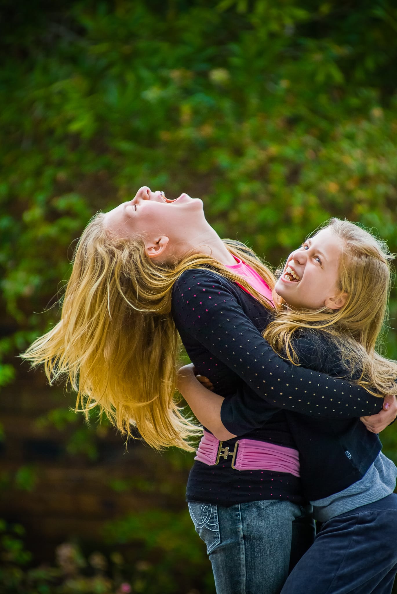 Two girls in a garden, one throwing her head back in pure laughter — Arnold Szmerling Visual Legacy Artist